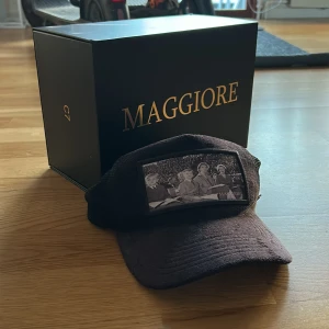 Svart sammetstruckerkeps Maggiore S3 c7 - Limited Edition svart keps från Maggiore S3 C7 med sammet framtill och mesh baktill. Kepsen har en unik patch med svartvit fotoprint på framsidan och Maggiore-logga på sidan. Kommer med box.