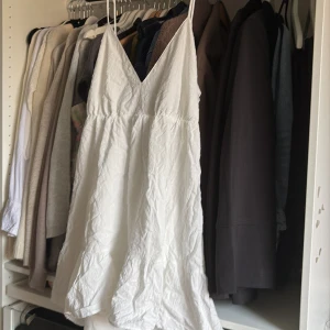 Vit somrig kortklänning med smala band - Supersöt vit kortklänning med smala axelband och v-ringning. Öppen i ryggen! Aldrig använd