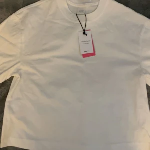 Vit t-shirt från Gina Tricot S - Fräsch vit t-shirt från Gina Tricot, kollektionen Elevated Basics. Klassisk rund hals och korta ärmar, perfekt för en clean och enkel stil. Tillverkad i mjuk bomull som känns skön mot huden. Passar dig som gillar minimalistiskt och stilrent.