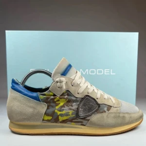 Philippe Model sneakers med camomönster - Sneakers från Philippe Model med beige mockadetaljer, blå häl, mesh framtill och coolt camouflagemönster i grönt, gult och grått på sidorna. Skorna har snörning och platt sula, perfekt för dig som gillar streetstyle och unika detaljer.