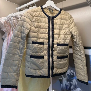 Beige Dunjacka med Mörkblå Detaljer  - Hej! Säljer denna supersnygga beiga dunjackan med mörkblå detaljer ifrån Mango eftersom den helt enkelt inte kommer till någon användning. Jackan är i mycket fint skick då den endast blivit använd  1-2 gånger. Perfekt om du vill klä upp en outfit lite! Om du skulle ha några funderingar är det bara att höra av dig, annars går det superbra att trycka på ”köp”. 