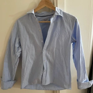 Ljusblå skjorta från RYVLS Stockholm - Klassisk ljusblå skjorta från RYVLS Stockholm i storlek 164. Skjortan har lång ärm, med krage. Den är större i storleken och skulle säga att den passar xs, sitter perfekt på för dig som är ca 170 lång