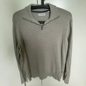 Beige half zip-tröja Jack & Jones - Snygg beige tröja från Jack & Jones i storlek S. Tröjan har en klassisk krage och half zip-dragkedja framtill. Långärmad och i mjukt material som passar perfekt till lager-på-lager. Enkel och stilren design som funkar till många outfits.