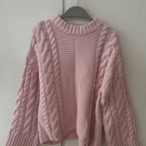 Rosa stickad tröja från Gina Tricot - Superfin ljusrosa stickad tröja från Gina Tricot i storlek XS men väldigt oversized i storlek. Tröjan har grova flätstickade detaljer på ärmar och sidor samt ribbad halsringning. Perfekt för kyliga dagar och riktigt mysig att ha på sig.