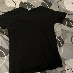 Svart basic t-shirt i bomull, M - En svart, enkel t-shirt i storlek M. Modellen är klassisk med rund hals och korta ärmar, perfekt för en clean och stilren look. Tillverkad i Turkiet, troligtvis i mjuk bomull som känns skön mot huden. Passar dig som gillar minimalistiska plagg.