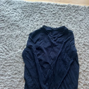 Svart långärmad tröja Springfield  - Svart långärmad tröja från Springfield i storleken kan va lite svår så skriv om ni har frågor . Tröjan har knappar vid halsen och är tillverkad i mjuk bomull. Enkel och stilren modell som passar perfekt till jeans eller chinos.