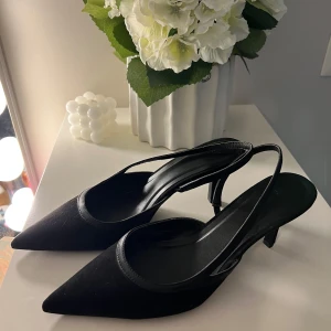 Klackskor med spetsig tå - Snygga svarta klackar med spetsig tå och låg klack från HM. Skorna har en öppen häl med smal rem runt foten och är tillverkade i ett material som ser ut som mocka. Aldrig använda🖤