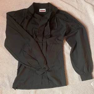 Svart blus - Svart knytblus som passar XS. Den är i mycket bra skick och är figursydd med ballong ärmar!