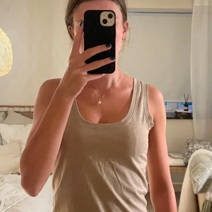 Beige linnetopp från Take Off - Säljer en beige linnetopp från Take Off i storlek M. Toppen har rundad halsringning och är ärmlös. Tillverkad i en mjuk mix av återvunnen polyester, bomull och elastan som ger en skön stretchig känsla. Perfekt till jeans eller shorts!