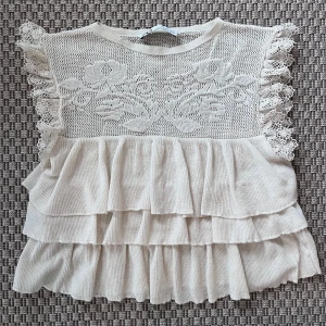 Beige volangblus med spets från Zara S (XS) - Zara virkad elfenbensfärgad blus, storlek S men liten i storlek så passar även XS  En maska har har gått uppe i kanten. En händig kanske kan sy. Se bild 2