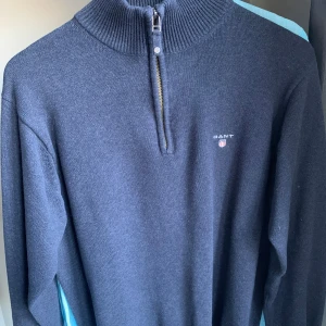 GANT quarter zip - Snygg mörkblå stickad tröja från GANT med halv dragkedja och ribbad hög krage. Tröjan har lång ärm och diskret logga på bröstet. Skriv för frågor eller fler bilder!