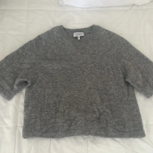 Grå stickad tröja från & Other Stories - Mysig grå stickad trekvartsärmad tröja från & Other Stories, Stockholm Atelier. Tröjan har en loose passform med kortare ärmar och rund halsringning. Materialet är mjukt, föuffigt och varmt, perfekt inför hösten!!