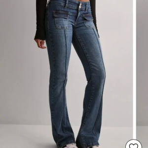 Blå jeans med fickdetaljer och dubbla knappar - Säljer ett par snygga blå jeans med coola fickor framtill och dubbla knappar i midjan. Jeansen har raka ben och klassiska bakfickor. Materialet är jeans och passformen är normal. Perfekt för dig som gillar streetstyle och vill ha något unikt i garderoben.