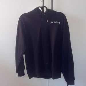 Marinblå hoodie Ma Chérie Gina Tricot - Marinblå hoodie från Gina Tricot med vit text 'Ma Chérie' och två hjärtan på ryggen. Tröjan har huva med snörning och långa ärmar. En av metall-grejerna på snörerna har lossnat annars bra skick. Tvättas innan köp!