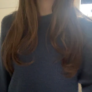 Mörkblå stickad tröja med rund hals - Mysig mörkblå stickad tröja med rund hals och långa ärmar. Tröjan har en enkel, klassisk design utan mönster eller detaljer och är tillverkad i ett mjukt stickat material som känns skönt mot huden. Perfekt för kyliga dagar och enkel att matcha med jeans eller kjol.