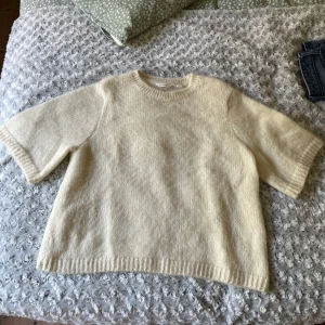 Vit stickad tröja från Dobber - Säljer en supermysig beige/vit stickad tröja från Dobber i storlek M. Tröjan har rund hals, ribbade muddar och halvkort ärm som ger en chill och modern vibe. Perfekt att styla med kjol eller jeans för en enkel men snygg look.