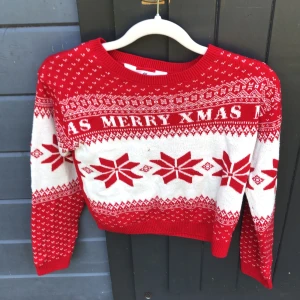 Röd jultröja med snöflingor från H&M - Säljer en röd och vit jultröja från H&M i storlek 134/140. Tröjan har ett klassiskt julmönster med snöflingor och texten 'MERRY XMAS' över bröstet. Den är stickad, har rund hals och långa ärmar. Perfekt för att maxa julstämningen!
