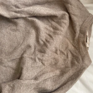 Beige stickad tröja från lager157 - Mysig beige stickad tröja från lager157 i storlek xs. Tröjan har en klassisk rund hals och långa ärmar med ribbade muddar. Perfekt för dig som gillar neutrala färger och vill ha en enkel, stilren look. Materialet är mjukt och skönt mot huden.