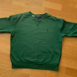 Grön sweatshirt från Polo Ralph Lauren - Snygg grön sweatshirt från Polo Ralph Lauren. Storlek är barn 10-12 men sitter som xs i vuxenstorlek det finns några små fläckar på ärmen som syns i bild fem men de går  förmodligen bort i tvätten. Vid snabbt köp är priset inte hugget i sten