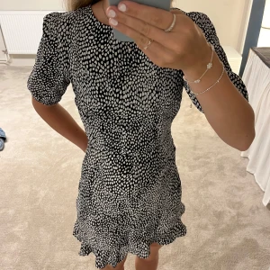 Svartvit prickig kortklänning NA-KD - Säljer en svartvit kortklänning från NA-KD med prickigt mönster. Helt ny utan prislapp, aldrig använd! Har en snygg öppning i ryggen också. Storlek 34