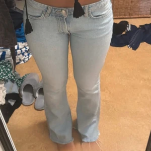 Bootcut ljusblå jeans - Snygga ljusblå bootcut jeans med klassisk femficksdesign och råa kanter vid benslut. Jeansen har låg midja och är tillverkade i mjukt denim som ger en skön passform. Perfekta för dig som gillar en avslappnad och trendig stil.