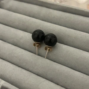 Svart pärlörhängen  - Ett par stilrena örhängen med rund, svart pärla och silverfärgad stift. Klassisk design som ger en clean och elegant vibe. Perfekta om du gillar minimalistiska smycken med lite edge. Säljs som par.