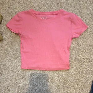 Rosa croppad ribbad topp - Säljer en rosa croppad topp med ribbad struktur. Toppen har rund hals och korta ärmar, perfekt för dig som gillar en enkel men snygg stil. Passar dig som vill ha en slim fit och gillar att sticka ut med färg. Storlek xxs💓