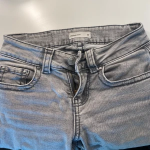 Gråa super lågmidjade jeans - Snygga gråa lågmidjade jeans från Gina Tricot. Dom är i storlek 32 och passar mig perfekt och jag är 160cm lång 🤍 jag har sprättat upp dom där nere (kolla sista). Skriv för frågor och jag är öppen för prisdiskutioner 💋