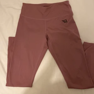 Rosa leggings från ICANIWILL, storlek S - Snygga ljusrosa leggings från ICANIWILL med hög midja och svart logga på höften. Tillverkade i stretchigt material med 85% polyester och 15% elastan, perfekta för träning eller chill. Sitter tight och följer kroppen för en sportig look. Nästan aldrig använt