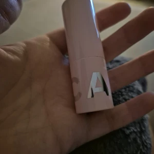 Cocoa Couture Lip Balm från CAIA - Säljer ett Cocoa Couture Lip Balm från CAIA i en snygg ljusrosa hylsa med silvriga bokstäver. Läppbalsamet har en mörkbrun ton och kommer i en klassisk stickform. Perfekt för dig som vill ha återfuktade läppar med en hint av färg.