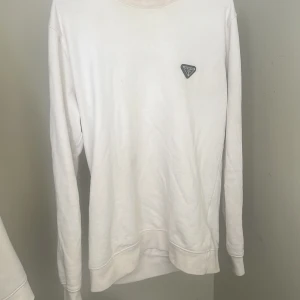 Vit sweatshirt från Prada - Säljer en stilren vit sweatshirt från Prada med klassisk rund halsringning och diskret logga på bröstet. Tröjan har lång ärm och är tillverkad i mjukt bomullsmaterial, perfekt för en clean och avslappnad look. Pris kan diskuteras 