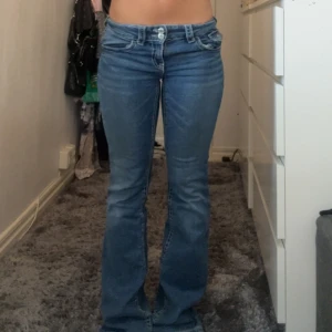 Blå bootcut jeans låg midja - Snygga blå jeans med bootcut passform och låg midja. Jeansen har klassiska fem fickor och en cool tvätt som ger en avslappnad vibe. Perfekta för dig som gillar retrostil och vill ha ett par jeans som sticker ut lite extra.