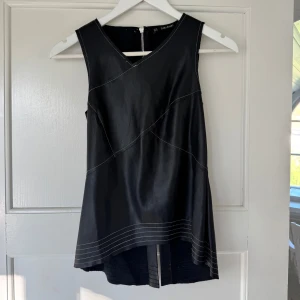 Svart topp i lädereffekt - Så cool och snygg topp i läder-effekt 🤍 Så najs till fest!! Cool öppning där nere i ryggen