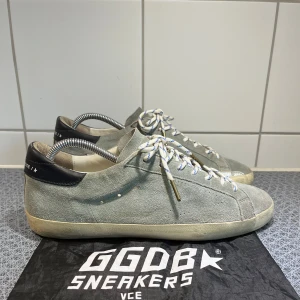 Golden goose skor  - Tjena säljer nu dessa tvärfeta Golden goose skorna i mocka. Skick (8,5/10). Dustbag ingår. Självklart äkta. Tveka inte på att höra av dig vid minsta fråga eller fundering. Inte den klassiska silvriga stjärnan utan en mer subtil stjärna. Gör skorna än mer bärbara i och med att de blir mer nertonade. Men också coolare