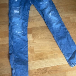 Blå skinny jeans med slitningar - Snygga blå jeans med skinny passform och slitna detaljer på framsidan. Klassisk femficksmodell med bakfickor och ljus tvätt. Perfekta för dig som gillar en trendig och avslappnad stil.