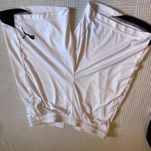 Vita sportshorts från Puma - Snygga vita shorts från Puma med svart logga på sidan och svarta detaljer upptill. Modellen har elastisk midja med snörning för skön passform. Tillverkade i lätt polyester med DryCell-teknologi som håller dig torr under träning eller match.