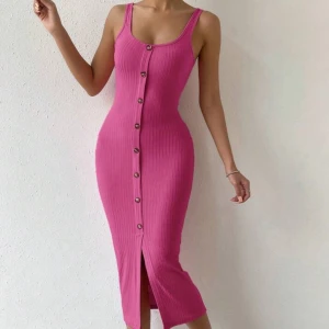 Rosa ribbad klänning med knappar - Snygg rosa ribbad klänning med knappar framtill och slits nertill. Ärmlös modell med smala axelband och figurnära passform som framhäver siluetten. Perfekt för dig som vill sticka ut med en färgstark look.