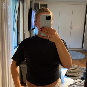 Svart t-shirt från 157, storlek M - En svart t-shirt från 157 i storlek M. T-shirten har klassisk passform med korta ärmar och rund halsringning. Enkel och stilren design utan mönster, perfekt till jeans eller shorts. Materialet känns mjukt och följsamt mot huden.