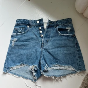 Blå jeansshorts med slitna detaljer - Snygga blå jeansshorts med hög midja och råa, fransiga kanter. Loose fit🥰🥰