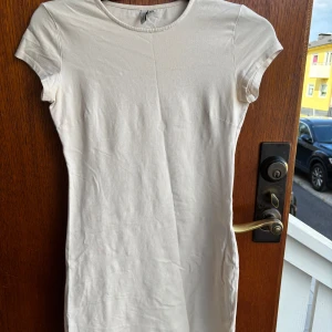 Vit kortklänning från NLY Trend - Enkel och stilren vit kortklänning från NLY Trend. Klänningen har rund halsringning, korta ärmar och är figurnära i modellen. Perfekt för dig som gillar minimalistisk och clean stil. Tillverkad i mjuk bomull för en bekväm känsla.