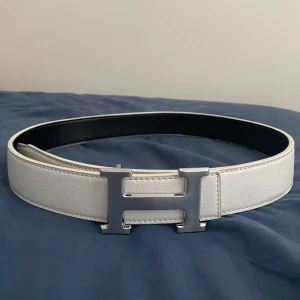 Vändbart bälte med silver H-spänne - Säljer ett vändbart bälte i svart och vitt skinn med ikoniskt H-spänne i silver. Bältet har stilren design och passar perfekt till jeans eller kostymbyxor. Bredden är klassisk och materialet känns lyxigt och hållbart. Bara att skriva vid frågor och priset går såklart att diskutera!