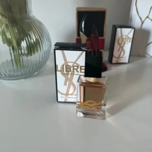 Yves Saint Laurent Libre parfym - Säljer en elegant YSL Libre Eau de Parfum i en stilren glasflaska med svart och guld detaljer. Parfymen har en lyxig känsla och kommer i originalkartong med guldiga YSL-loggor. Perfekt för dig som gillar exklusiva dofter. NYPRIS 430