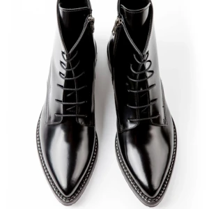 Svarta spetsiga snörade boots i skinn - Säljer ett par svarta glansiga handgjorda boots med spetsig tå och snörning. Skorna är i äkta italienskt skinn/läder med robust sula och dragkedja på sidan. Använd 2 gånger. Storlek 39. 