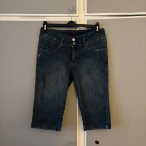 Jeansshorts capri från Bik Bok - Snygga mörkblå jeansshorts i caprimodell från Bik Bok. Klassisk femficksdesign med dubbla knappar fram och coola dragkedjor på bakfickorna. Gjorda i stretchig denim av bomull och lite elastan för skön passform. Perfekta för en chill sommarstil.