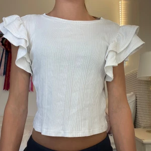 Vit volang topp - Superfin vit topp med ribbad struktur och korta volangärmar, från Gina Young i strl 146-152💗