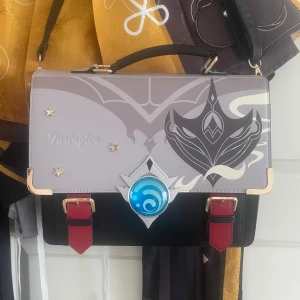 Childe/Tartaglia väska - Säljer denna tartaglia itabag/väska för jag är lowkey inte i min genshin era längre💔 Köpte den från dokidoki och har haft den sen maj 2024. Har använt den typ 3 gånger. Man får 2 st band så man kan ha den som en ryggsäck eller ha bara ett band ♡ 