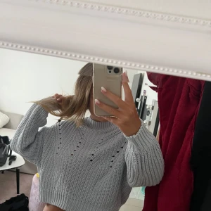 Ljusgrå stickad tröja Gina Tricot - Superfin ljusgrå stickad tröja från Gina Tricot. Tröjan har ett snyggt hålmönster framtill, ribbade muddar och hög hals. Perfekt till höst och vinter för en chill men trendig look.