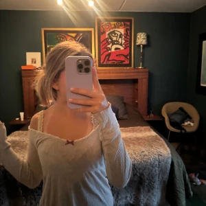 Odd Molly Grå ribbad  med rosett - Supersöt grå ribbad omlottop från Odd Molly med lång ärm, v-ringning och spetskant. Liten vinröd rosett framtill ger en gullig detalj. Perfekt till jeans eller kjol för en chill look. Den har ett litet hål bid bröstet men inget som syns. Det ger inte heller gått mer upp sen jag köpte den!