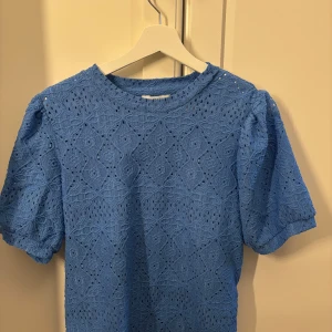 Blå spetsblus från vila (object)  - Supersöt blå blus från Object med korta puffärmar och rund hals. Blusen har ett detaljerat spetsmönster över hela plagget och är perfekt för dig som gillar en romantisk och trendig stil. Luftig och lätt, passar perfekt till jeans eller kjol. 💙använd ca 1 gång därav ingen lapp! 🌸