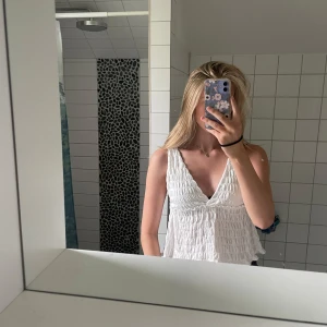 Vit omlott linnetopp med v-ringning - Säljer en vit ärmlös linnetopp med omlott urringning! Väldigt snygg och prefekt för alla tillfällen!! Materialet är smockat vilket blir väldigt snyggt! Kontakta för fler bilder!